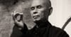Portrait of Thich Nhat Hanh holding a mudra, a hand gesture with the third finger bent and held by the thumb.
